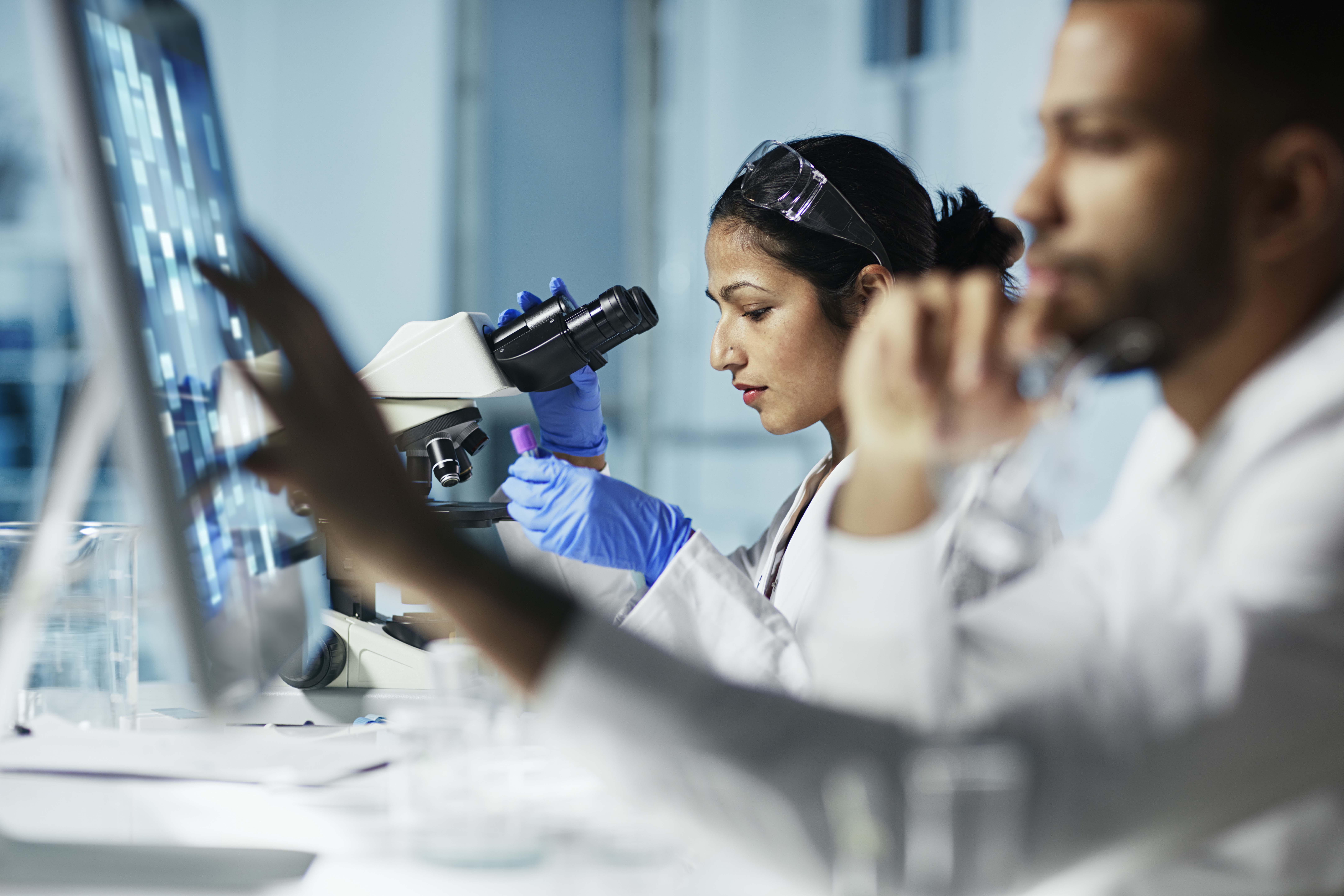 Scientist working on computer and microscope In modern laboratory