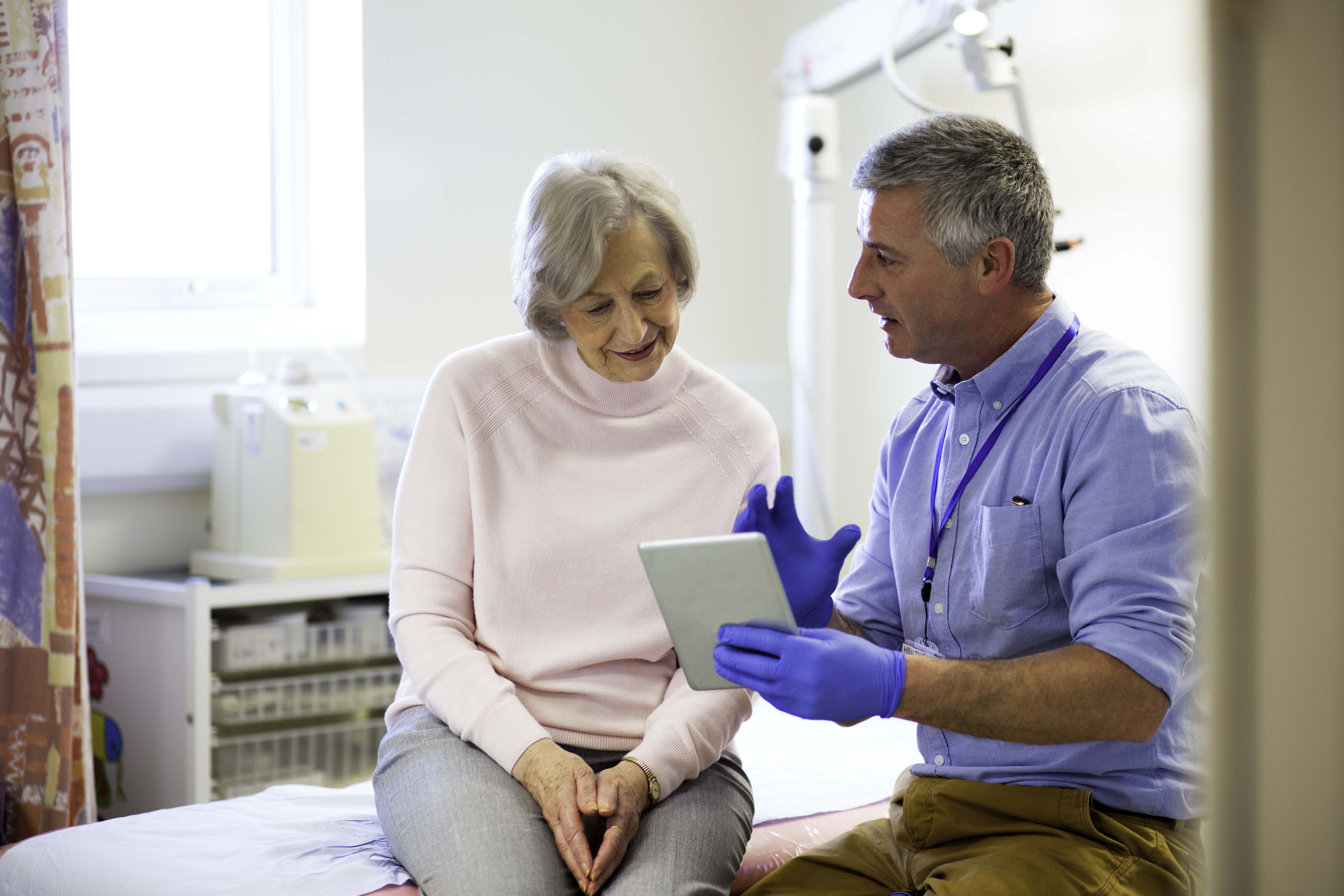 Doctor explaining results in an examination room holding a tablet