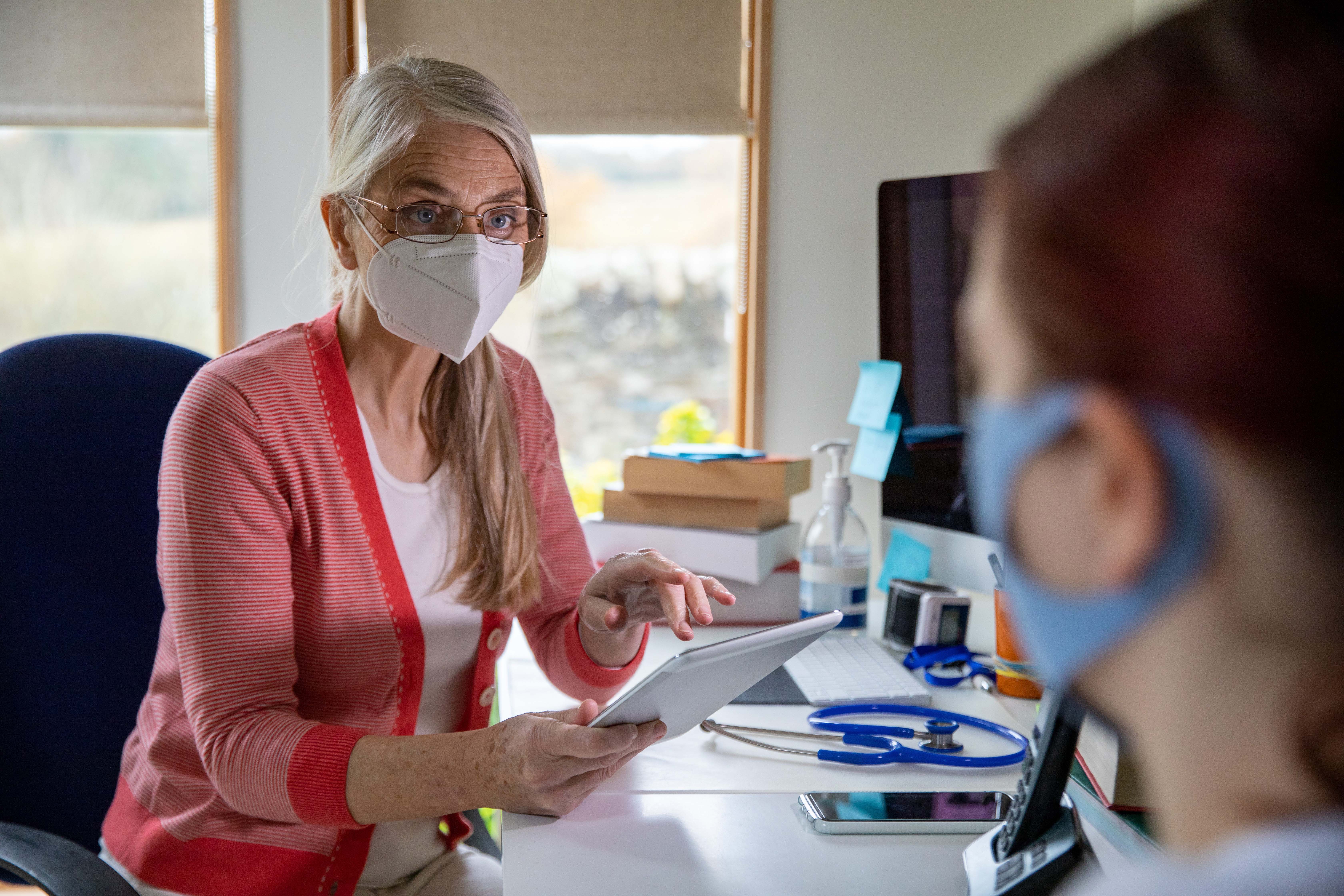 Doctor wearing a protective face mask working in a surgery during the Covid 19 pandemic.
