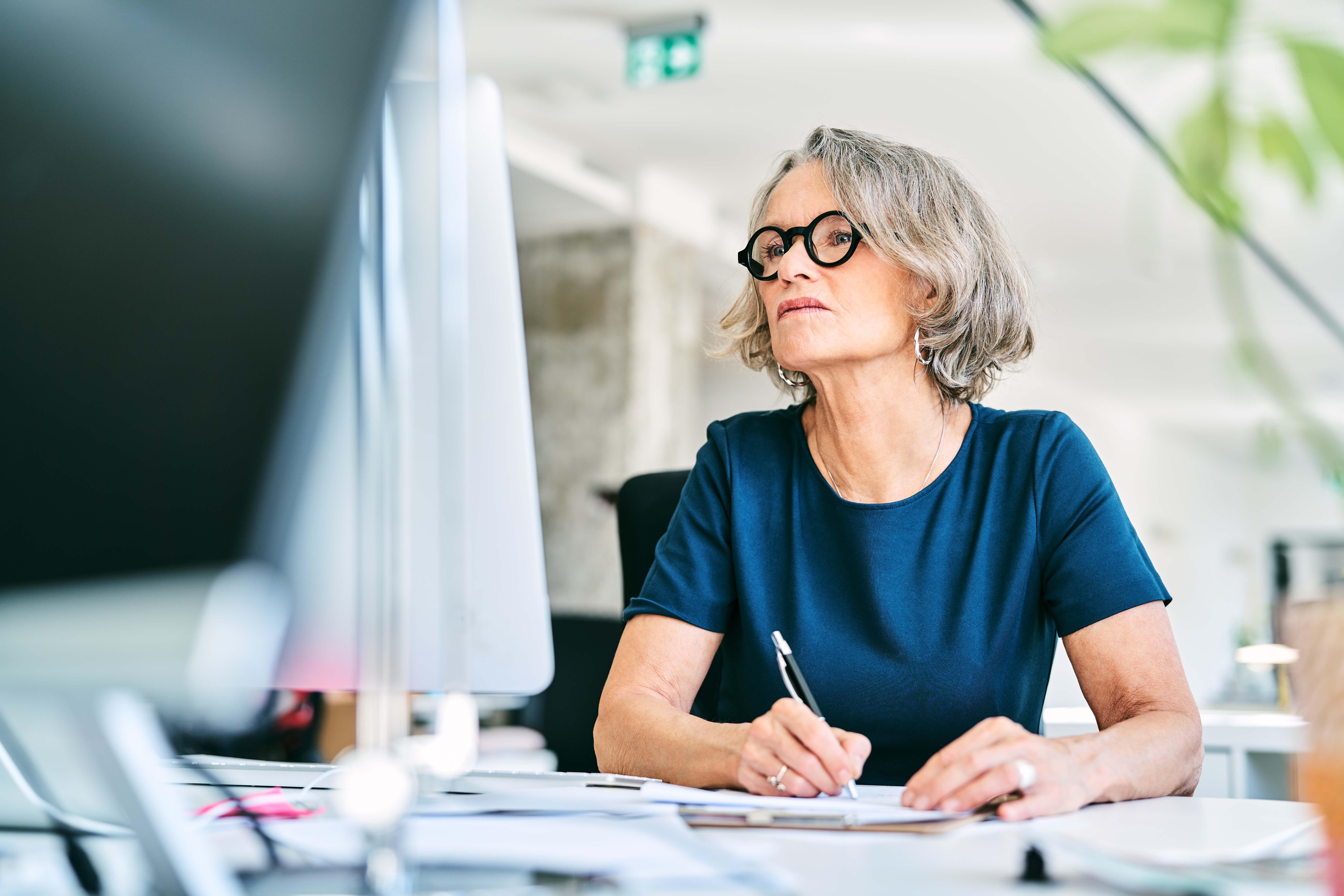 Consultant at her desk looking at PC wearing glasses