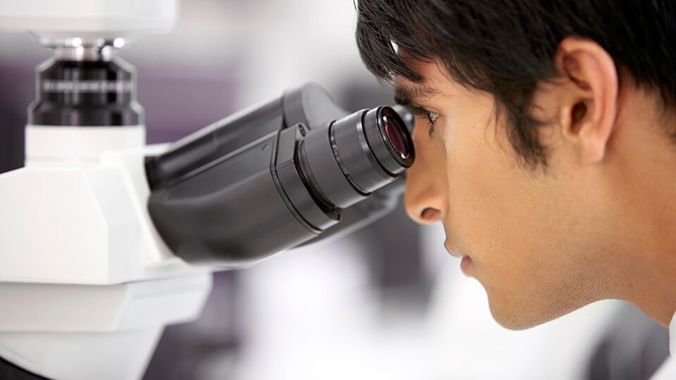 Close up of scientist looking through microscope