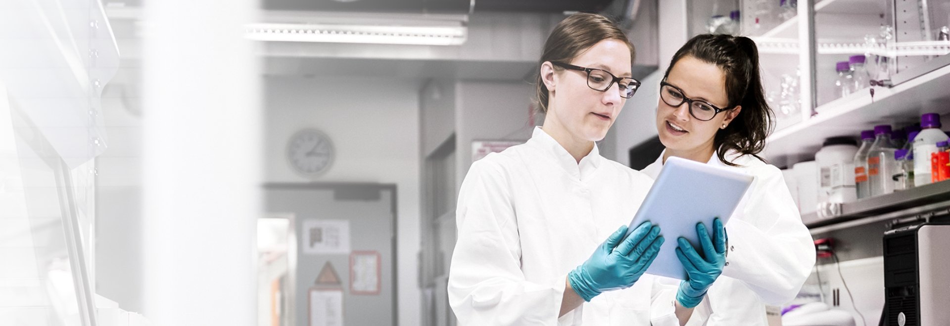 Two scientists standing in the laboratory and discussing data from experiment together