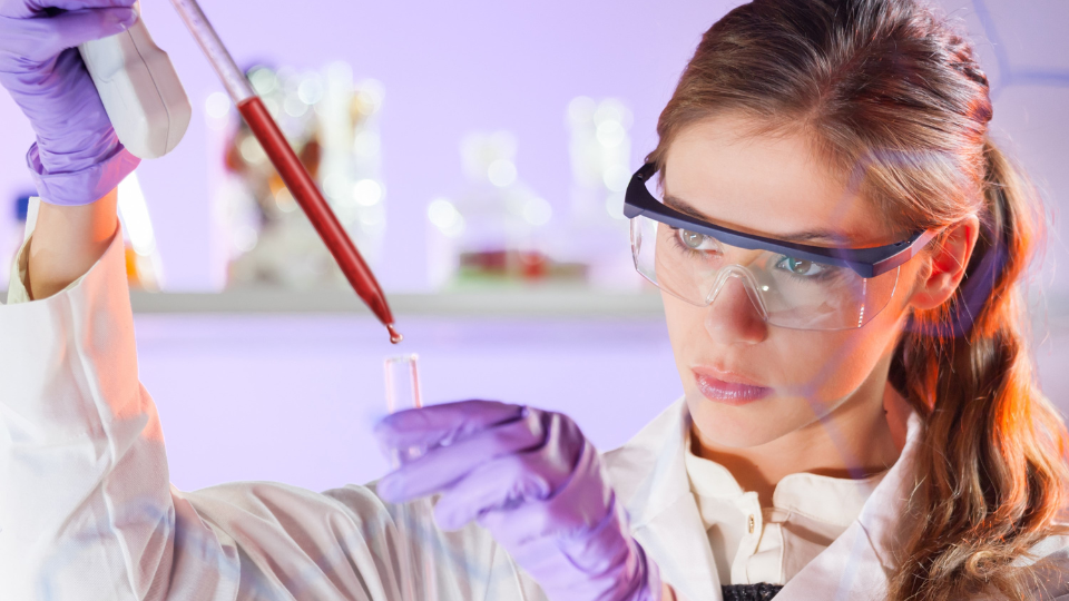 A woman in a lab coat holding a tube for HLA Transplant research